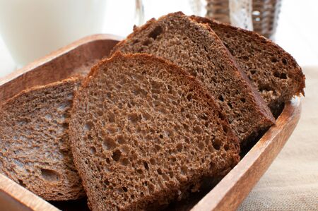 Rye bread slices in wooden plate close-up
