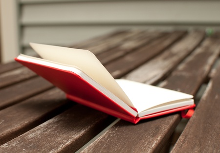 Red notebook open on wooden table outsideの写真素材