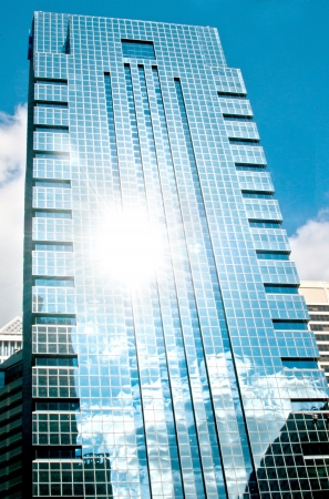 Skyscraper with sky sun and clouds reflection verticalのeditorial素材