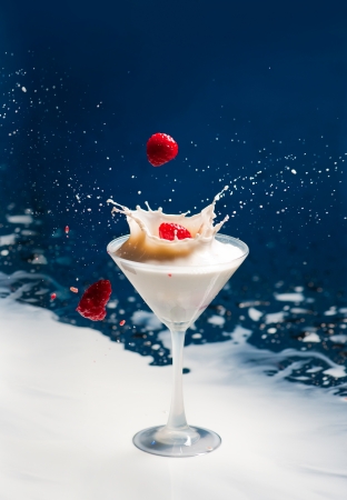 Raspberries falling into the glass with milkshakeの写真素材