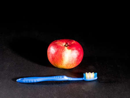 Blue toothbrush and red apple on black backgroundの写真素材