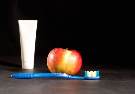 Toothbrush, toothpaste and apple on black backgroundの写真素材