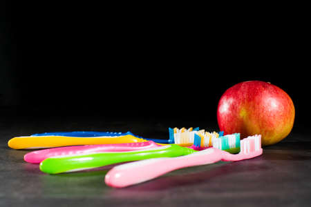 Background of colored toothbrushes and appleの写真素材