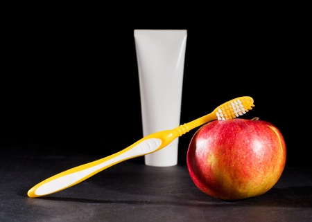 Toothbrush, toothpaste and apple on black backgroundの写真素材
