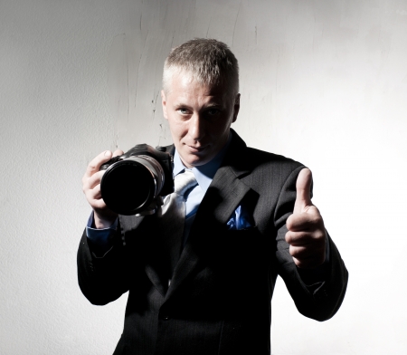 Positive photographer in a suit with a cameraの写真素材