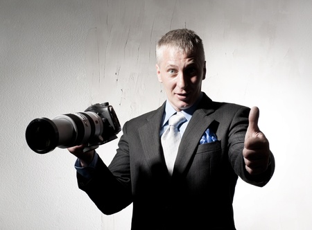 Positive photographer in a suit with a cameraの写真素材