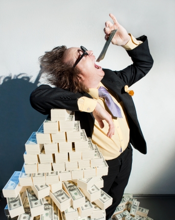 Greedy banker in glasses eats moneyの写真素材