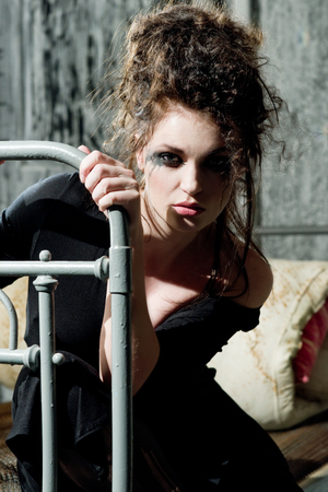 Young sad woman sitting on the old bedの写真素材