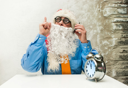 Santa Claus with the clock and the cellphoneの写真素材