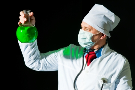 Doctor in surgical mask holding the flaskの写真素材