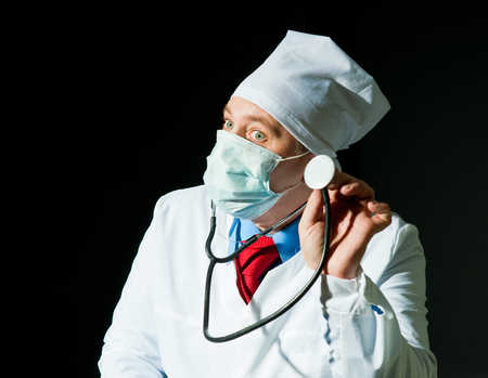 Doctor in surgical mask holding stethoscopeの写真素材