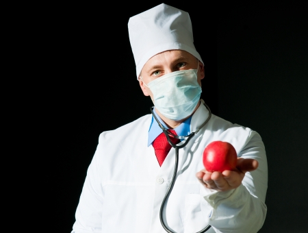 Doctor in surgical mask with the ripe appleの写真素材