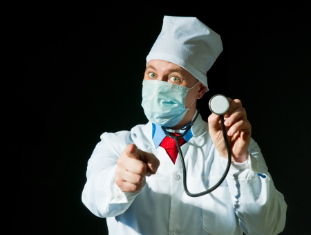 Doctor wearing a mask from the flu holding stethoscopeの写真素材