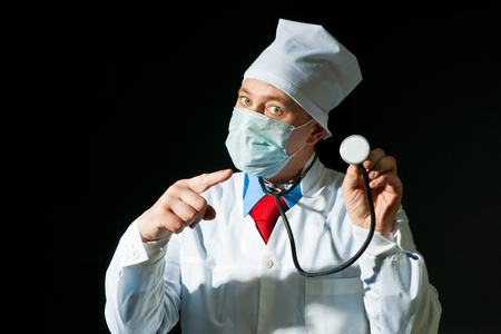 Doctor wearing a mask from the flu holding stethoscopeの写真素材