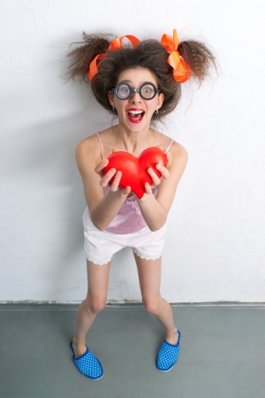 Funny girl with a red heart in the handsの写真素材