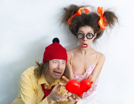 Funny man and girl with a red heart in the handsの写真素材
