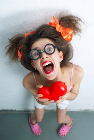 Funny girl with a red heart in the handsの写真素材