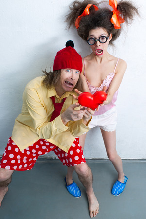 Funny man and girl with a red heart in the handsの写真素材