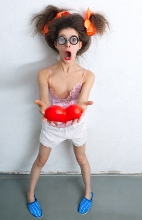 Funny girl with a red heart in the handsの写真素材