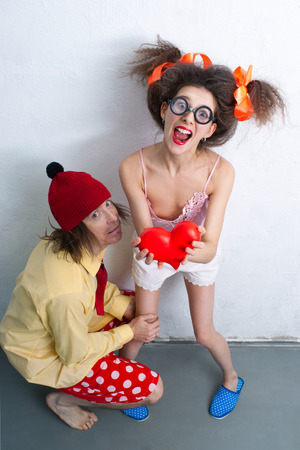 Funny man and girl with a red heart in the handsの写真素材