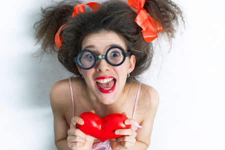 Portrait of funny girl with a red heart in the handsの写真素材