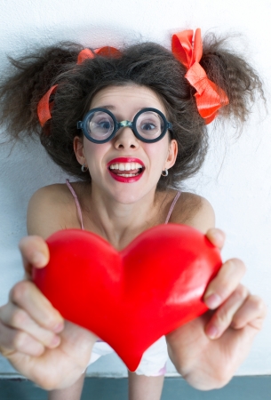 Portrait of funny girl with a red heart in the handsの写真素材