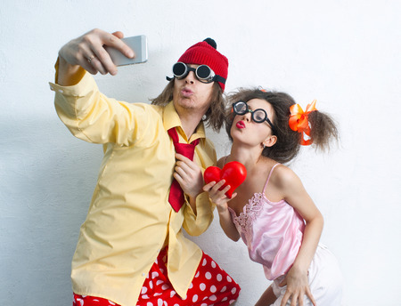 Bizarre couple in love is photographed on a mobile phoneの写真素材