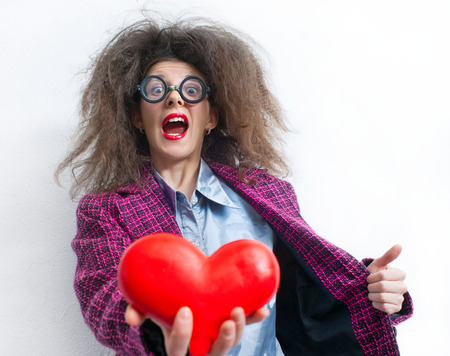 Portrait of funny girl with a red heart in the handsの写真素材