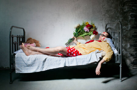 Tired man with bouquet lying on the bedの写真素材