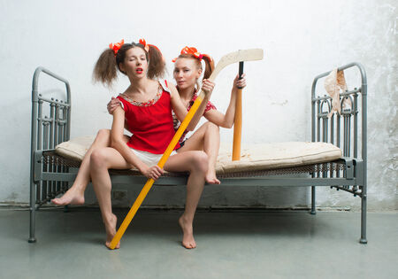 Two cheerful girls sitting on the bedの写真素材