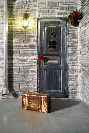 Old suitcase at the door and flower in the handle of doorの写真素材