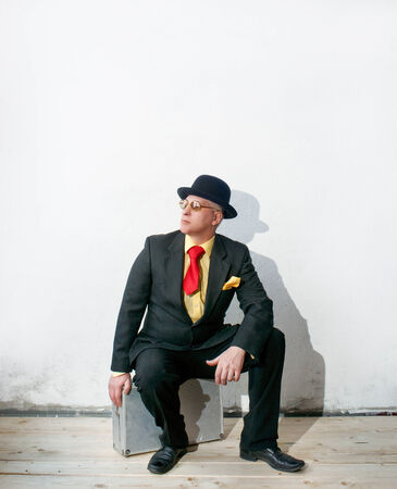 Businessman in black suit sitting on a suitcaseの写真素材