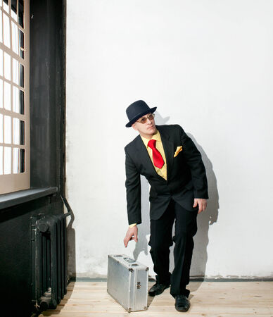 Businessman in black suit takes a suitcaseの写真素材