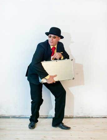 Businessman in black suit holding a suitcaseの写真素材