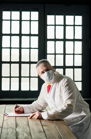 Doctor in the mask sitting at a table の写真素材