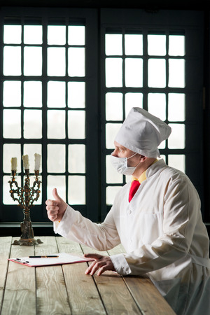 Doctor in the mask sitting at a table の写真素材
