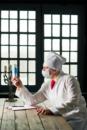Doctor in the mask sitting at a table の写真素材