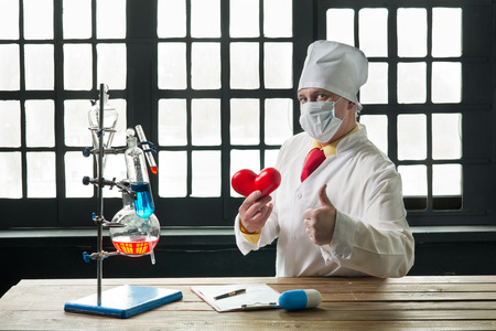 Doctor in the mask sitting at a table by the windowの写真素材