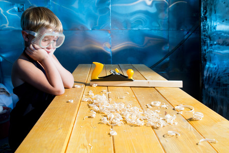 Small carpenter with the shaving plane at the table