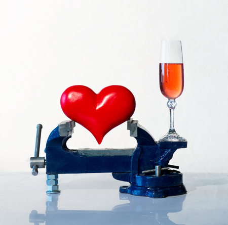 Heart is grip in a vice and wineglassの写真素材