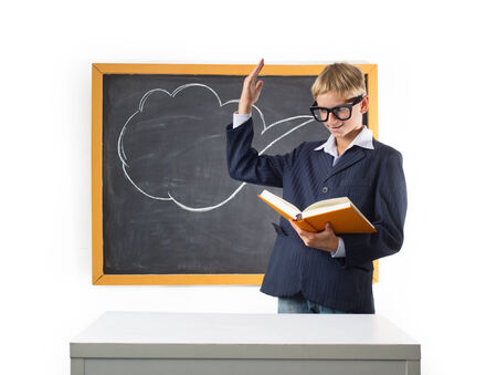 Erudite schoolboy stands at the blackboard with textbookの写真素材