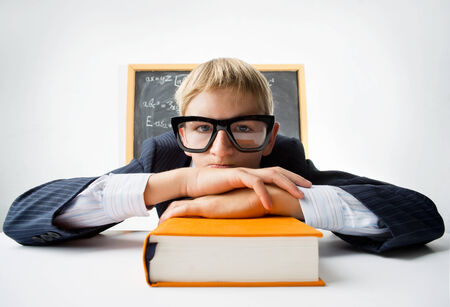 Erudite schoolboy sitting at the desk with textbook