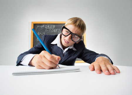 Erudite schoolboy sitting at the desk with pencilの写真素材