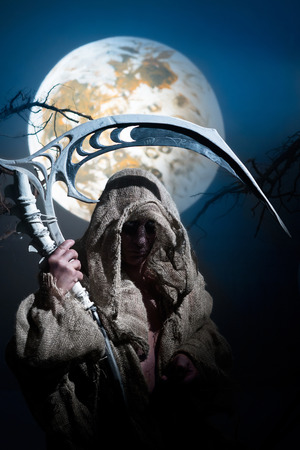 Ghost in rags with scythe on the background of the moonの写真素材