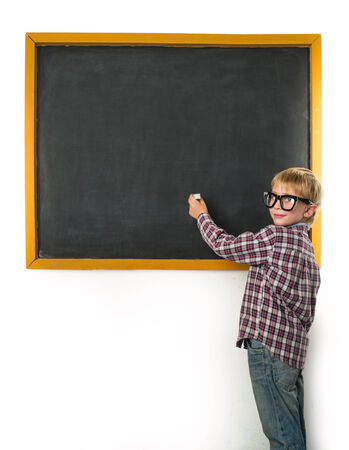 Schoolboy with a chalk stands at the blackboardの写真素材