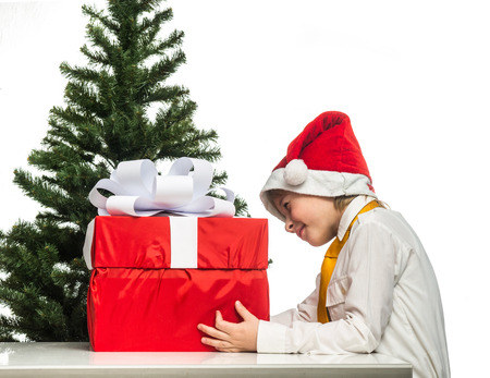 Little Santa with a gift near the Christmas treeの写真素材