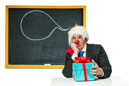 Sad Santa Claus with gifts near the blackboardの写真素材