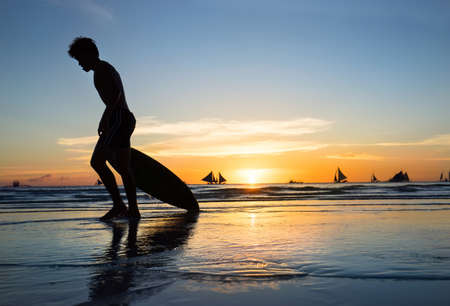 Silhouette of a surfer on the wave of the evening seaの写真素材