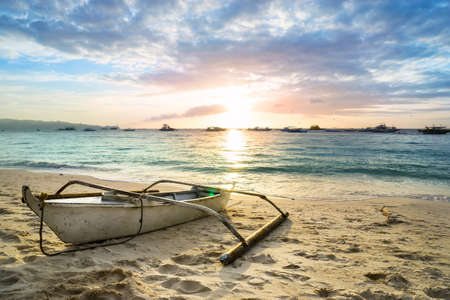 Sunset over the sea and the boat on the sandの写真素材