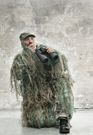 Frightened soldier in camouflage with binocularsの写真素材